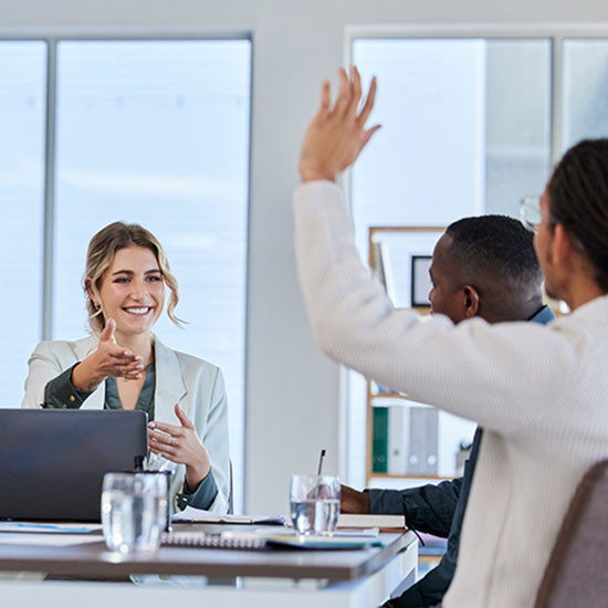 Positive office environment. Employee raising hand.