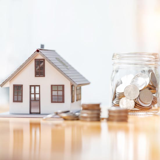 Home-mortgage-FEATURE -- Small Model house with a jar of coins and stacks of coins sitting next to it.