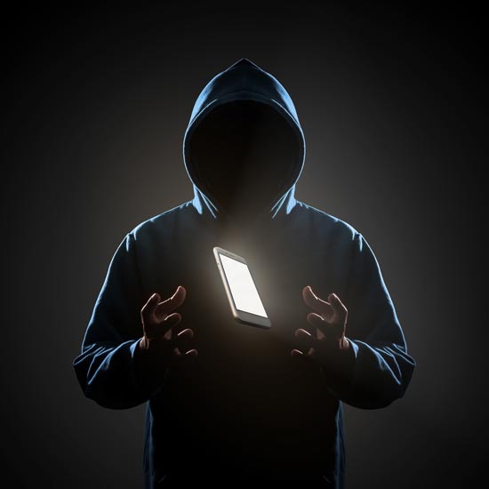 Hacker in a hoodie with a mobile phone hovering between his outstretched hands
